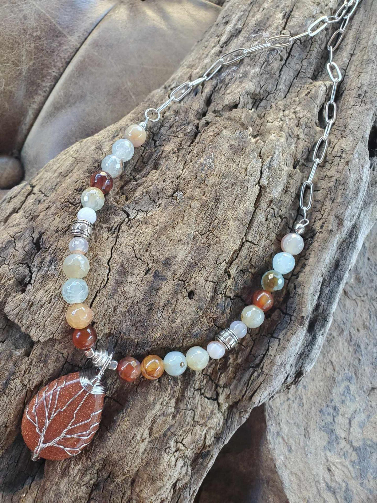Necklace with beads and a leaf pendant on a wooden surface